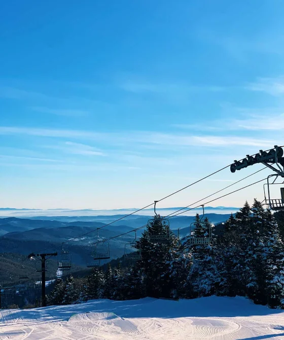 Panoramic view from Killington Mountain in the winter. Ski lifts under a blue sky.