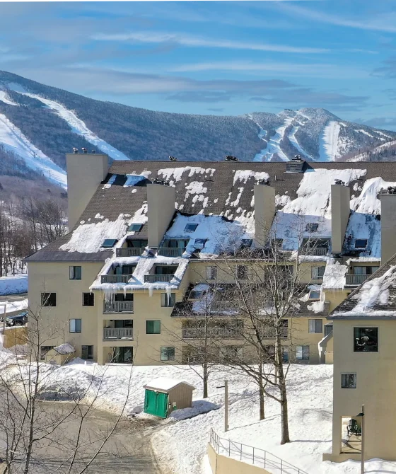 Aerial view of Killington's Mountain Green condominium complex in the winter, with Killington mountain seen behind.