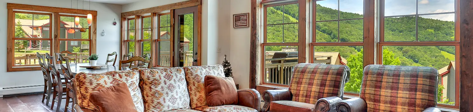 Large windows with mountain views at the living room of a luxury Killington rental.