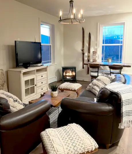 Interior of an apartment with ample couches, a view of the mountains, and a Smart TV.