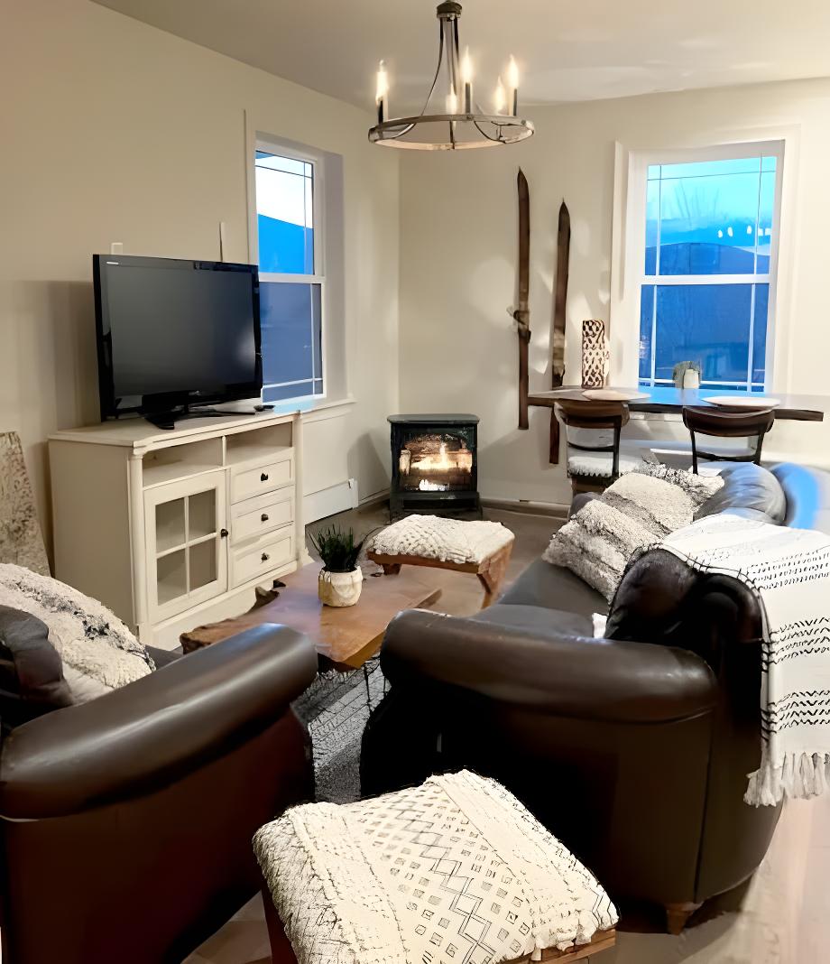 Interior of an apartment with ample couches, a view of the mountains, and a Smart TV.