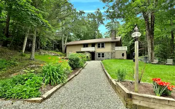 Entryway of a large home surrounded by trees and lawn.