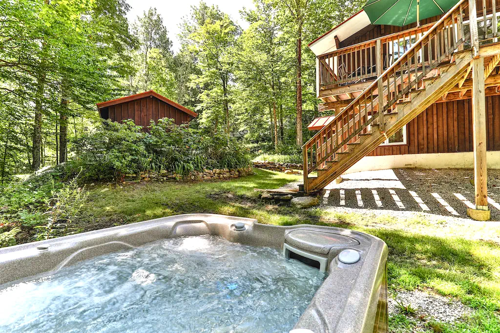 A Killington, VT cabin yard with a hot tub in front and birch trees behind.